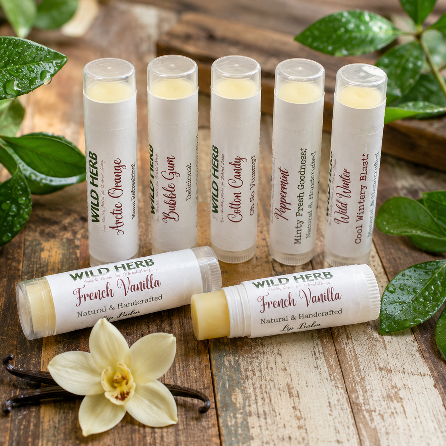 Six Wild Herb lip balm tubes arranged on a rustic wooden surface with green leaves, vanilla beans, and a white vanilla flower. The tubes show various flavors including Arctic Orange, Bubble Gum, Cotton Candy, Peppermint, Cool Mint Blast, French Vanilla, and Wild Water.