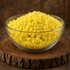 Clear glass bowl filled with yellow beeswax pellets 