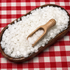 Wooden scoop in a bowl of white beeswax pellets on a red and white checkered tablecloth